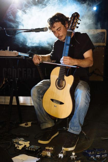 Photo de Paloo du groupe Swallow, jouant de la guitare à l'aide d'un archet